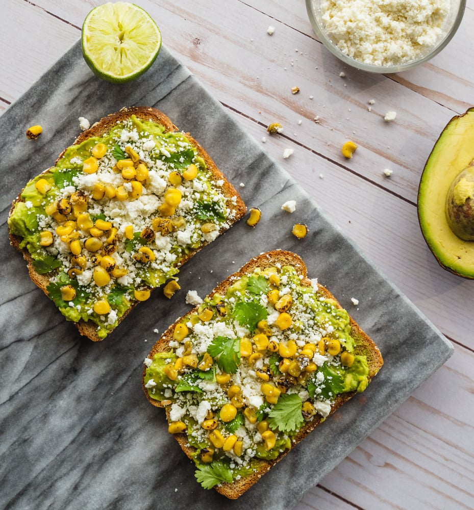 Mexican Street Corn Avocado Toast Recipe with Delicious Toast On A Serving Board With Cheese And Half An Avocado Beside It