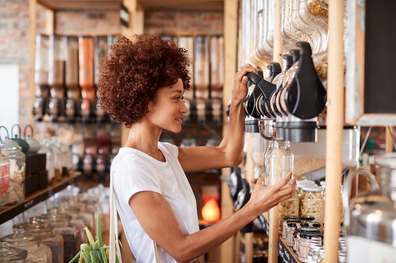 Environmentally conscious woman shopping for health food with zero-waste containers.