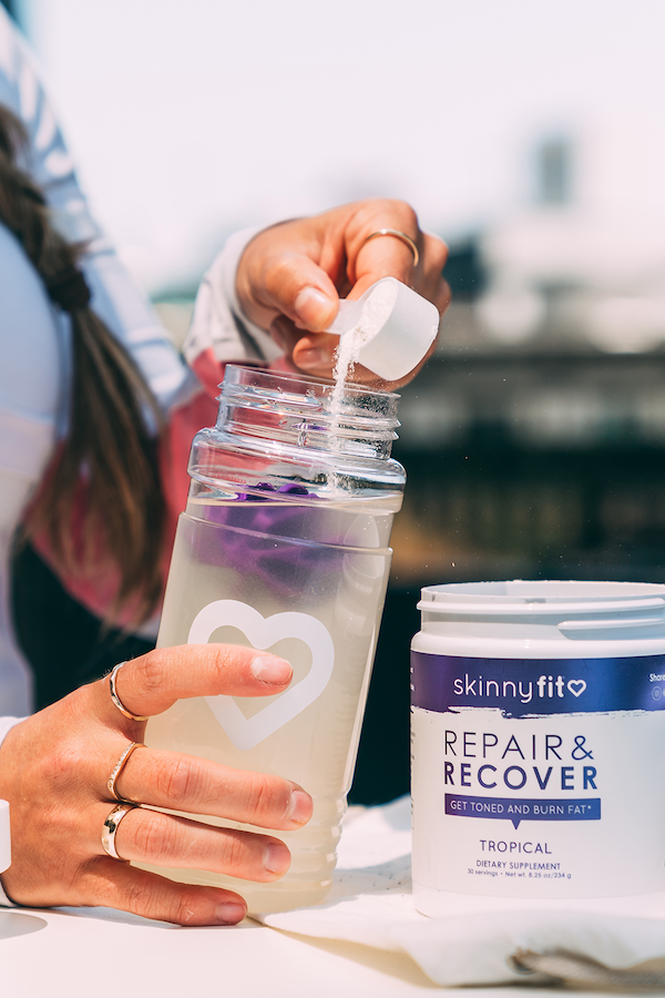 SkinnyFit electrolyte powder Repair & Recover being poured into a water bottle