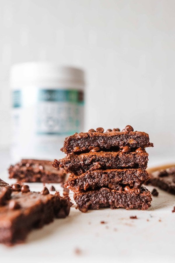 Healthy Brownies made with SkinnyFit Super Youth Chocolate Cake collagen, stacked on a table ready to be eaten. 