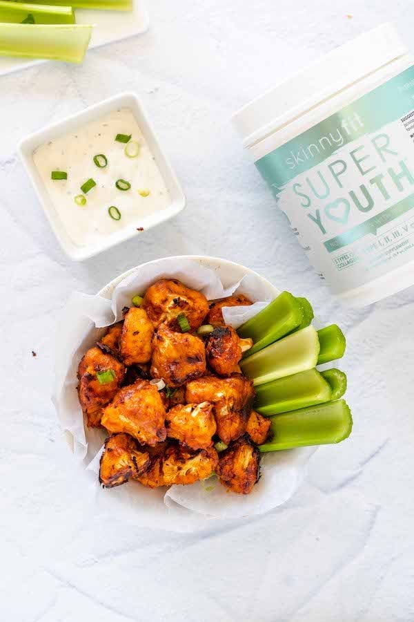 Buffalo cauliflower with chive dip and a celery, sitting by a jar of Super Youth unflavored collagen peptides