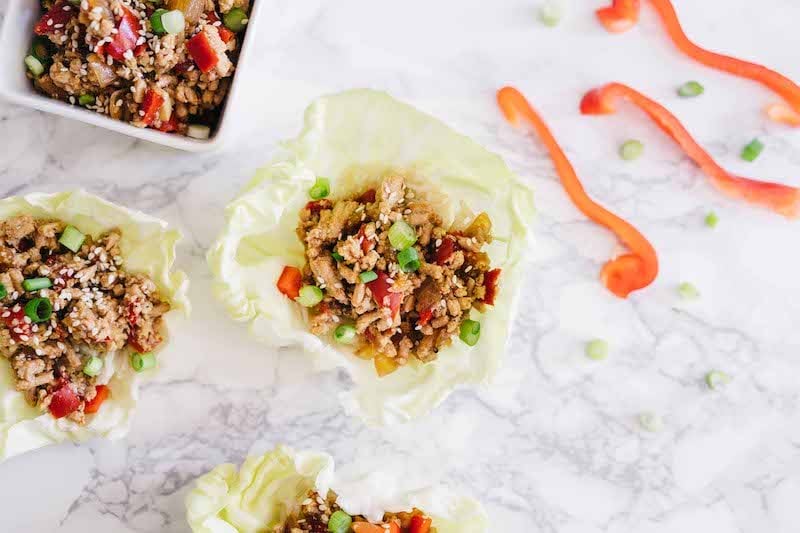 Thai lettuce wraps in iceberg lettuce cups and ceramic bowls.