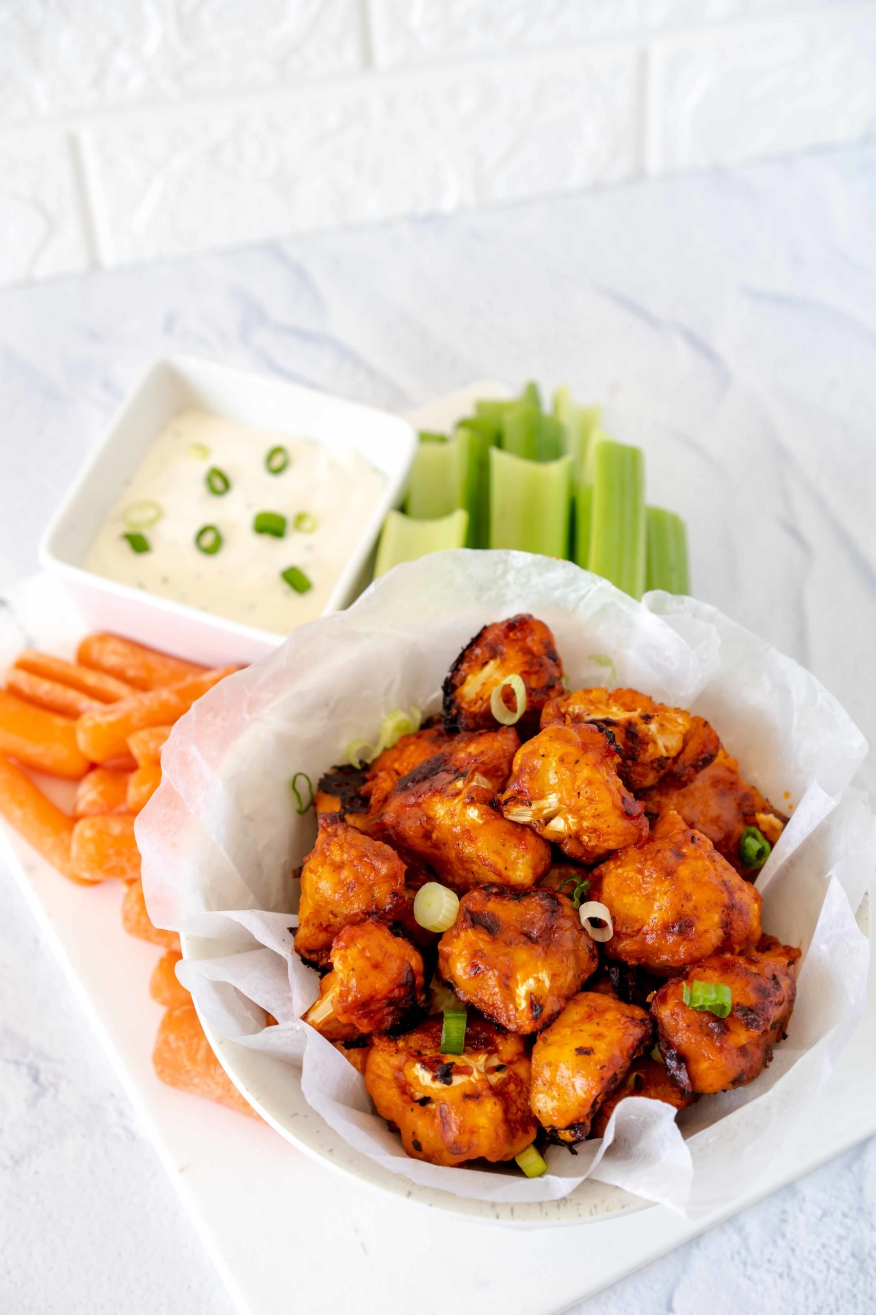 Freshly made buffalo cauliflower bites with Super Youth Unflavored collagen in a bowl with carrots, celery and side of chive dip