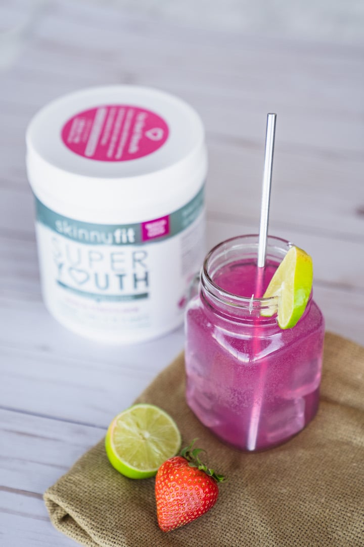 Tropical coconut water in a mason jar with the secret ingredient, Super Youth Tropical Punch collagen, in the background.