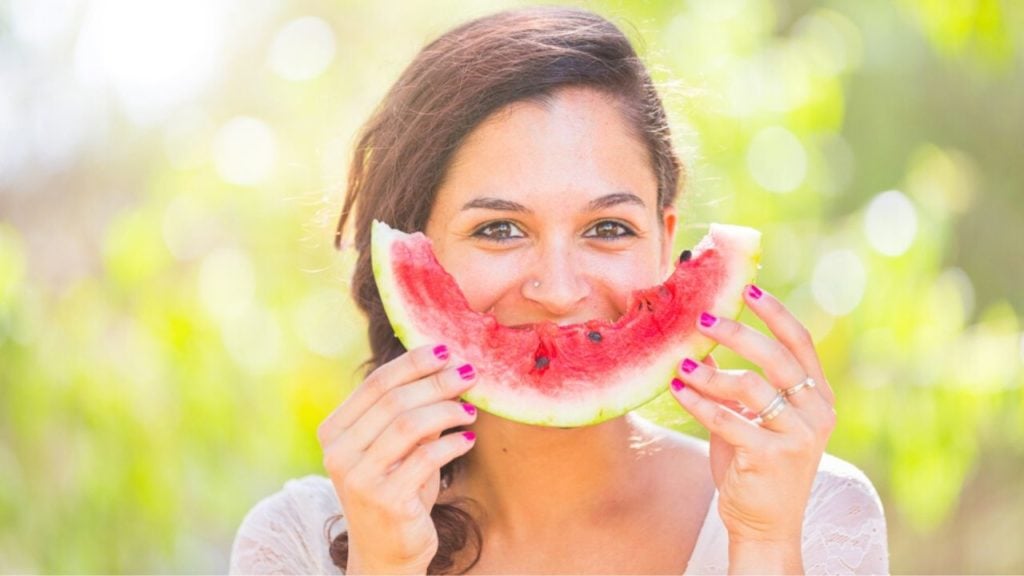 Woman eating a watermelon and smiling with it