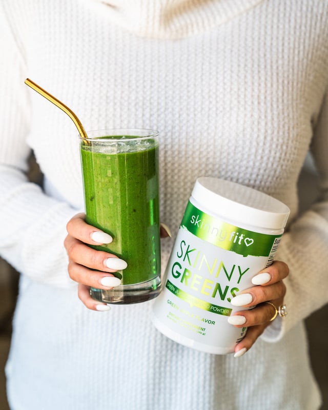 Woman holding SkinnyFit Skinny Greens as a side for bento box recipe.