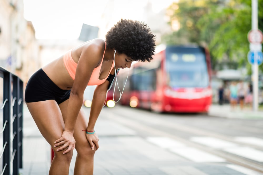 overtraining - woman trying to catch her breath while running