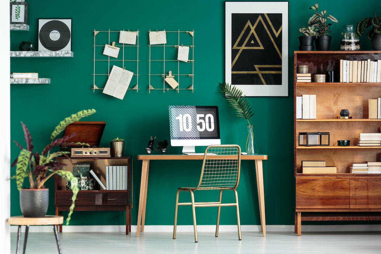 A home office using moody colors on the wall and surrounding furnishings.