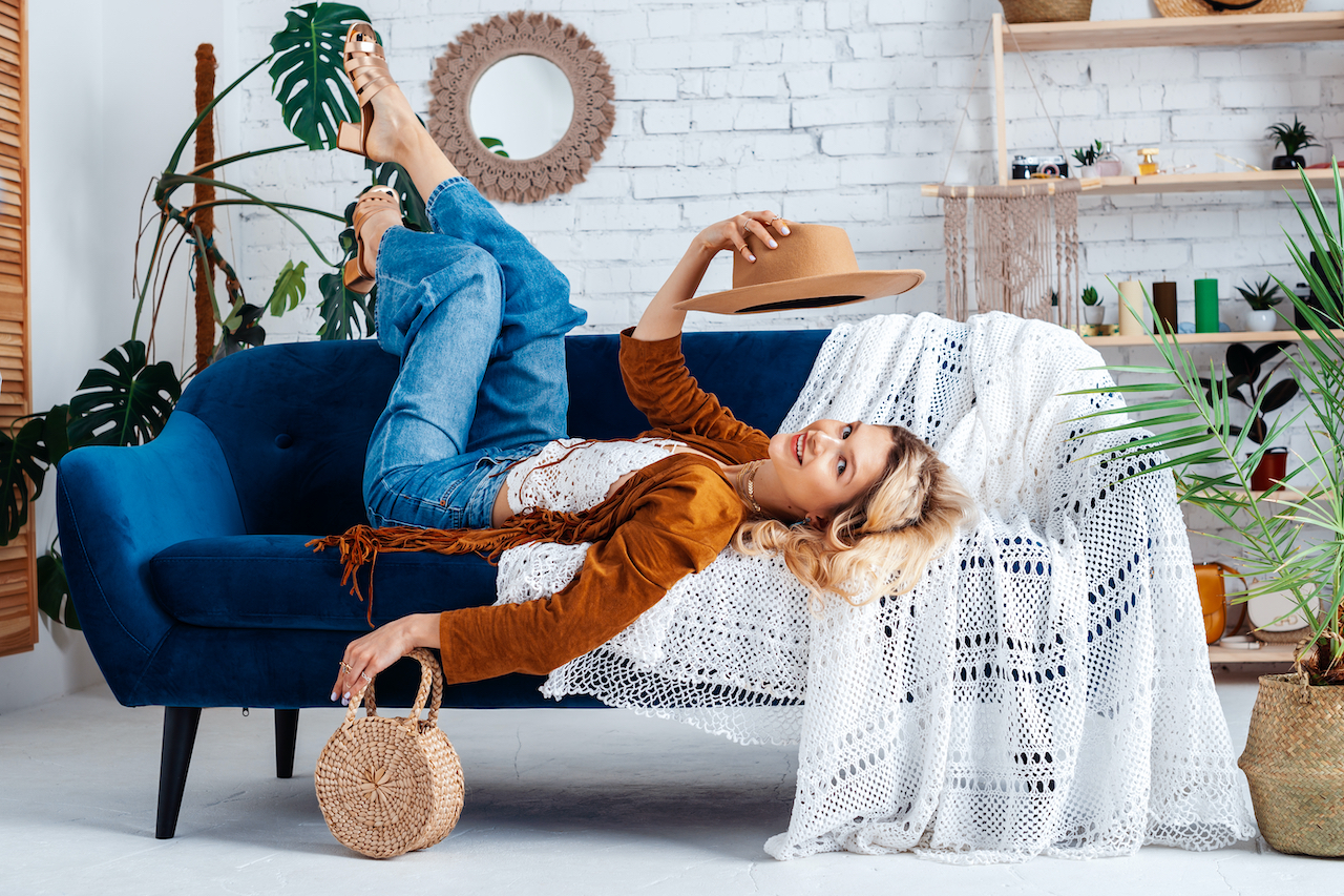 A woman laying on a Navy blue couch with a white throw that really accentuates the surrounding autumnal color scheme.