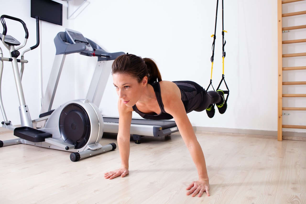 Woman performing a suspended pushup with TRX suspension training gear