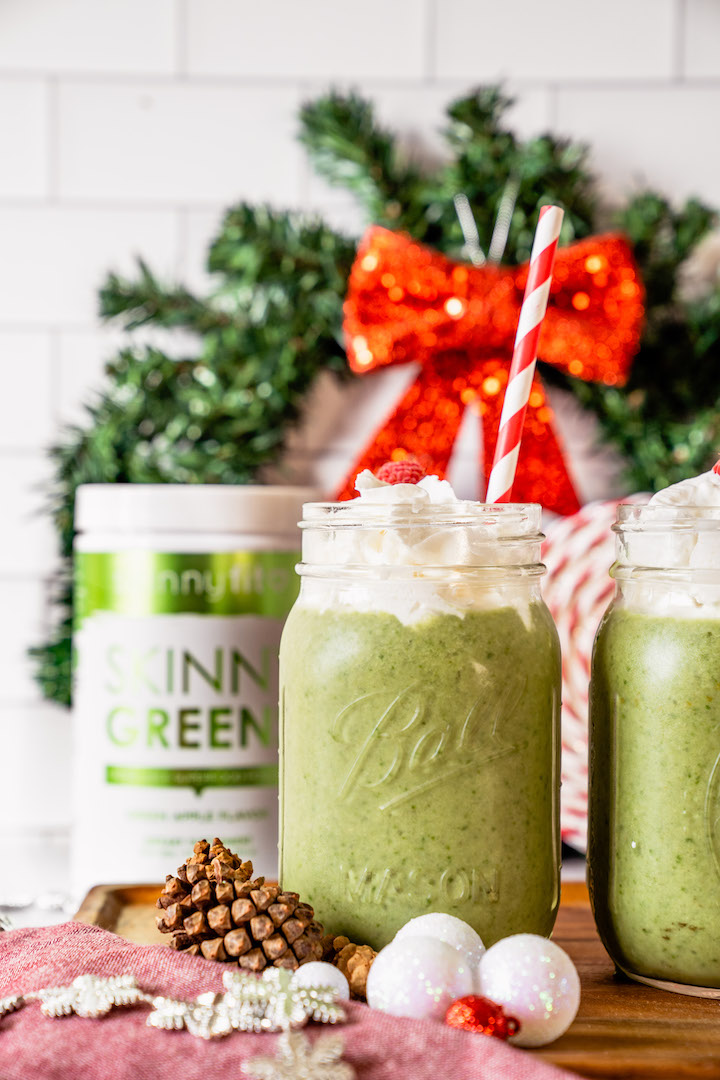 Grinch Smoothie in a mason jar with a container of SkinnyFit Skinny Greens behind it.