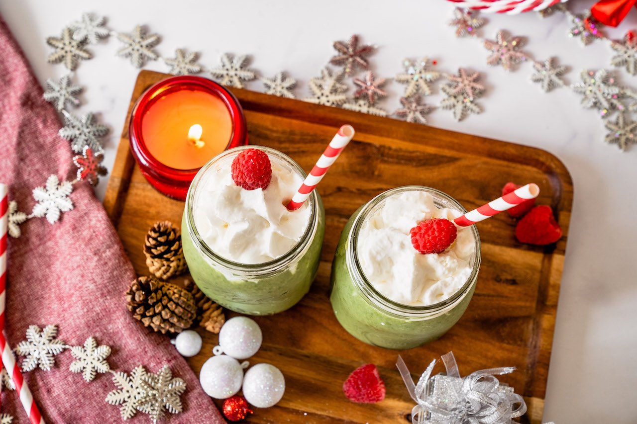 Grinch Smoothies with whip cream and raspberry toppings for extra holiday colors, as well as SkinnyFit Skinny Greens for slimming superfoods.