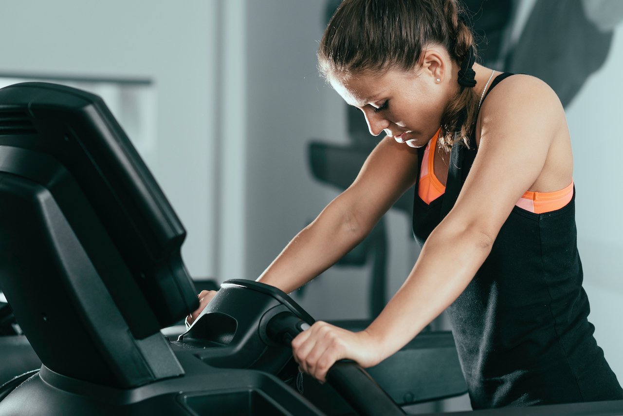 Woman on a treadmill feeling frustrated about hitting a weight loss plateau.